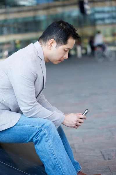 Ασιατικό άτομο κάθεται με το κινητό τηλέφωνο — Φωτογραφία Αρχείου