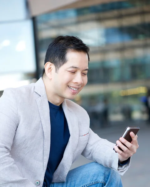Azjatycki człowiek uśmiechający się z telefonem komórkowym — Zdjęcie stockowe