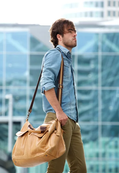 Elegante giovane uomo che cammina con borsa da viaggio — Foto Stock