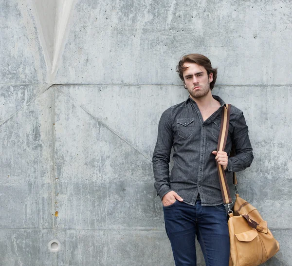 Jeune homme élégant posant avec sac de voyage — Photo