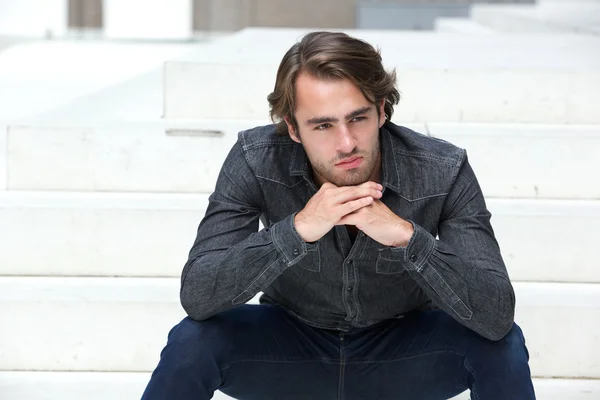 Young man sitting on steps outside — Stock Photo, Image