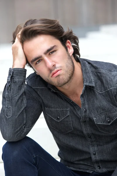 Young man sitting with hand in hair — Stock Photo, Image