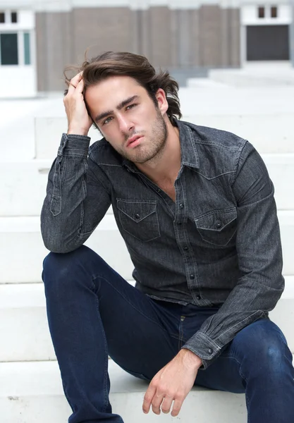 Cool guy sitting outside with hand in hair — Stock Photo, Image