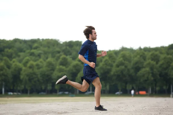 Athletic young man running outdoors — Stock Photo, Image