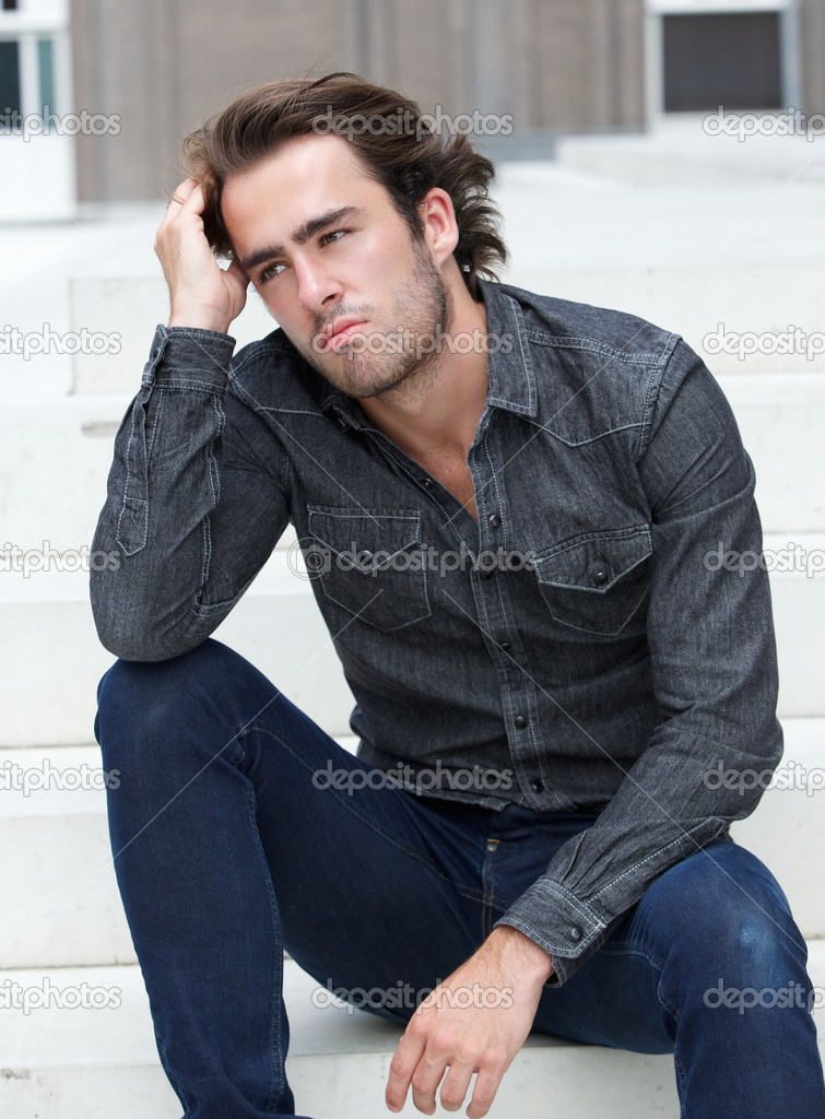 Man sitting alone outside with hand in hair