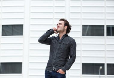 Mobil telefonda konuşurken gülümseyen genç adam