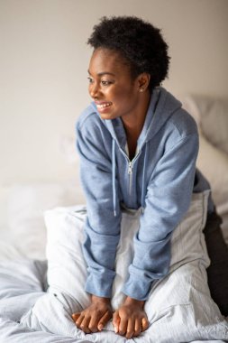 Portrait relaxed African American woman sitting in bed smiling
