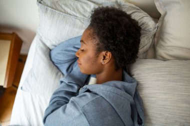 Top down portrait young African American woman sleeping in bed