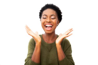 Close up portrait happy young African American woman laughing with hands in air and eyes closed by isolated white background 