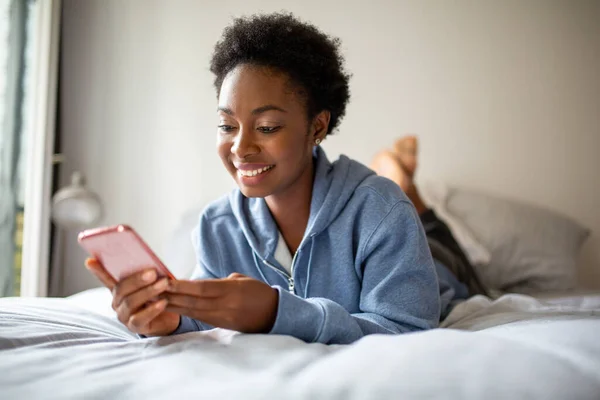 Portrait Smiling Young African American Woman Lying Bed Looking Mobile — Stockfoto