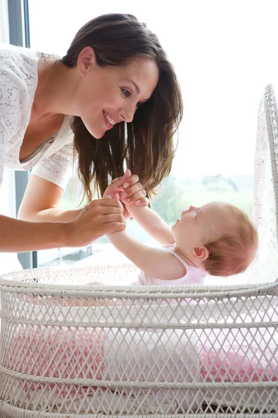 Madre sonriendo con un bebé en la cama — Foto de Stock