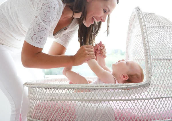 Mulher sorridente segurando bebê no berço — Fotografia de Stock