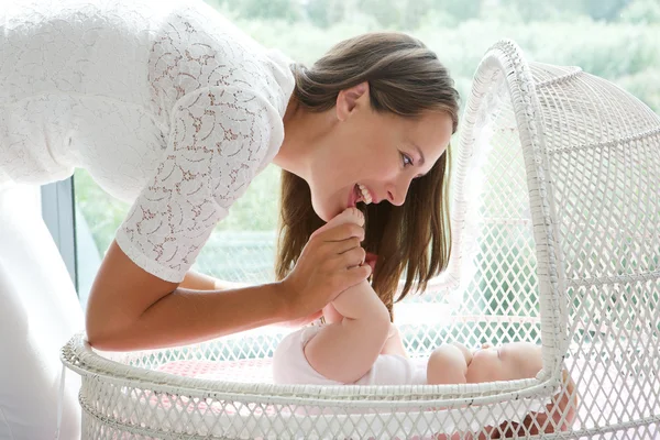 Mãe atraente brincando com o bebê no berço — Fotografia de Stock
