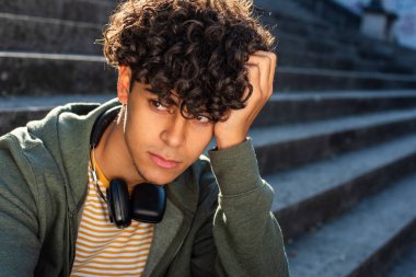 Close up portrait young guy sitting outside and thinking