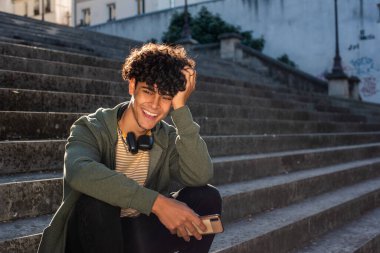 Portrait happy young guy sitting on steps outside
