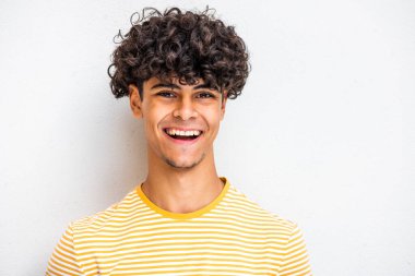 Close up face portrait young North African guy laughing by white wall
