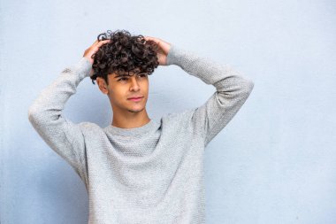 Portrait handsome young North African man posing with hands in hair