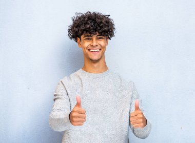 Portrait cool smiling North African young man with thumbs up hand sign