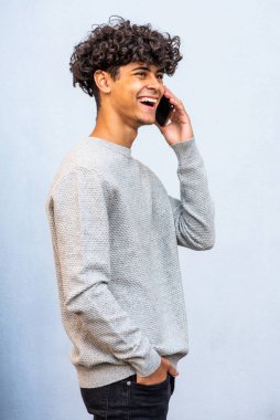 Profile portrait happy young man talking with cellphone by gray background 