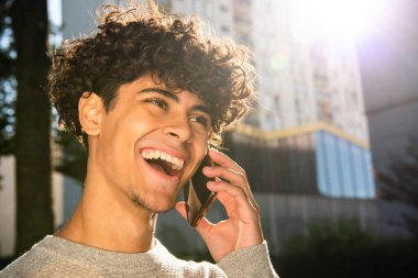 Close up portrait happy young arab man talking with mobile phone outside