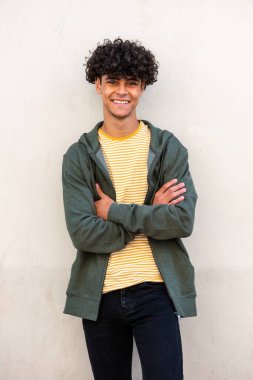 Portrait smiling young man with arms crossed by white wall