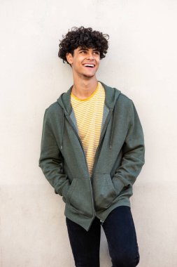 Portrait trendy young North African man laughing by white wall