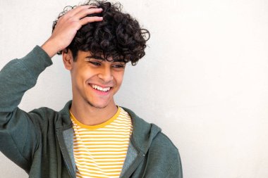 Close up portrait smiling young man with hand on head by white background 