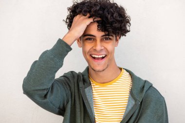 Close up portrait young man laughing with hand on head by white background 