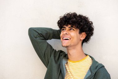 Close up portrait young man laughing with hand behind head against white background and looking away