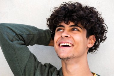 Close up portrait happy young man laughing with hand behind head and looking away