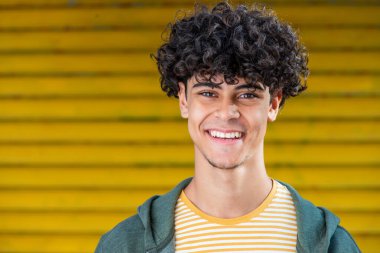Close up portrait young arabic man smiling by yellow background