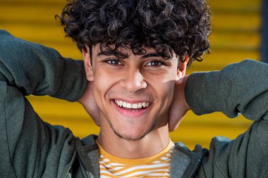 Close up portrait happy young North African man laughing with hands behind head