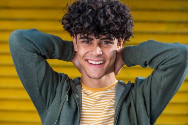 Close up portrait young arabic man smiling with hands behind head 