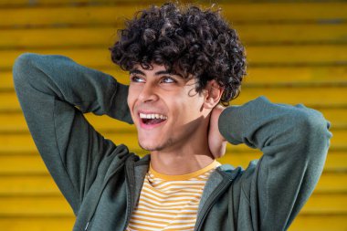 Close up portrait happy young arabic man laughing with hands behind head and looking away 