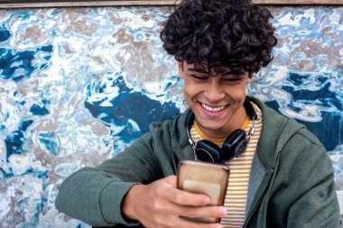 Close up portrait smiling young North African man looking at mobile phone