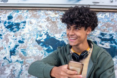 Close up portrait smiling young man holding mobile phone and looking away 
