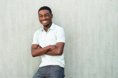 Portrait young African American laughing with arms crossed against wall