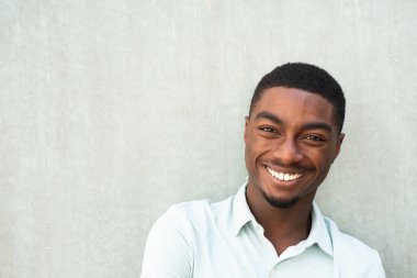Close up horizontal portrait handsome smiling young African American man against wall