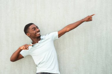 Portrait happy young African American man pointing fingers by background