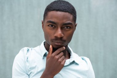 Close up portrait serious young African American man staring with hand to chin