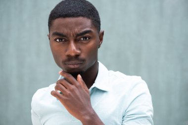 Close up portrait serious African American young man staring with hand to chin