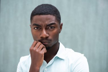 Close up portrait serious  young African American man staring with hand to chin