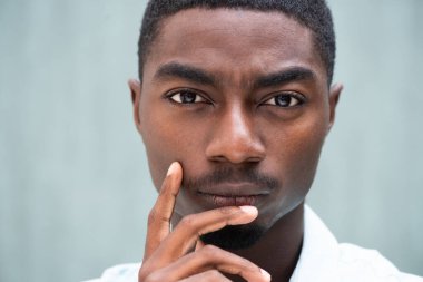 Close up portrait serious  young black man thinking staring with hand to chin