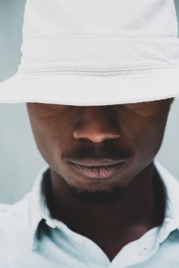 Close up portrait serious young African American man posing with hat covering eyes