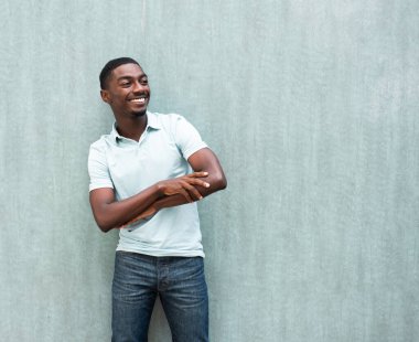 Portrait happy young black man with arms crossed and looking away