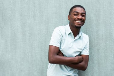 Portrait happy smiling young black man with arms crossed by wall