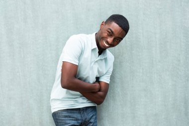 Portrait laughing young black man with arms crossed by wall
