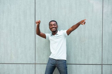Portrait young African American man smiling with arms raised and pointing fingers