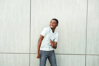 Portrait happy young African American man listening to music with earbuds and smart phone 