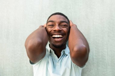 Close up front portrait laughing young African American man with hands behind head